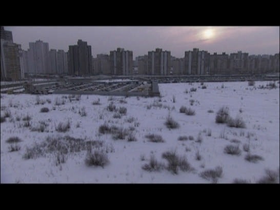 <i>Desniansky Raion</i>, 2007.
Made up of three parts, the film alternates scenes of order and chaos. It opens with a static shot of a ’70s high-rise housing block, a monumental triumph-gate built at the entrance of Belgrade. The film questions man’s traces in nature, between vandalism, romanticism and land art. Courtesy Cosmic Galerie (Bugada & Cargnel), Paris 