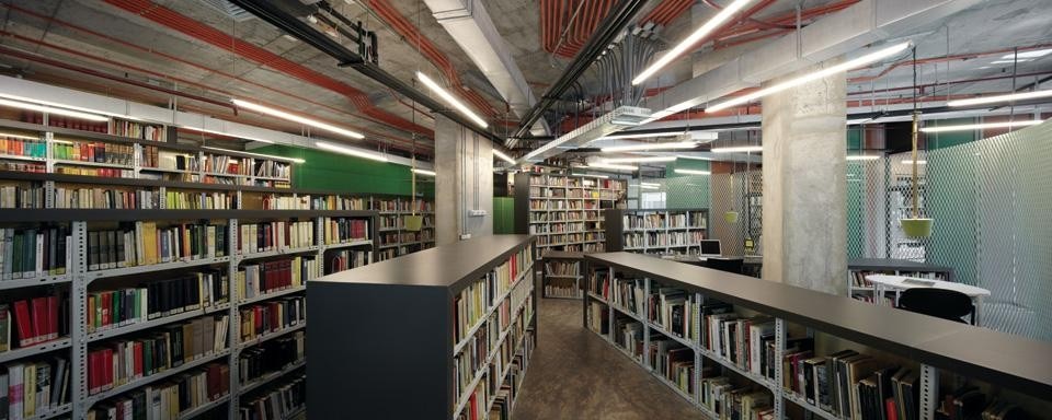 The existing furniture coupled with industrial metal shelving, backed with felt soundproofing panels, overturns the building's orthogonal geometry