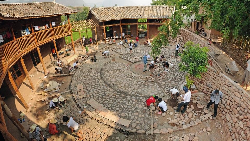 Local inhabitants taking part in laying the paving for the village’s new civic centre. Constructed along the river at the edge of the village, this building houses a health centre, a kindergarten, a shop, a library, an exhibition space and a dormitory