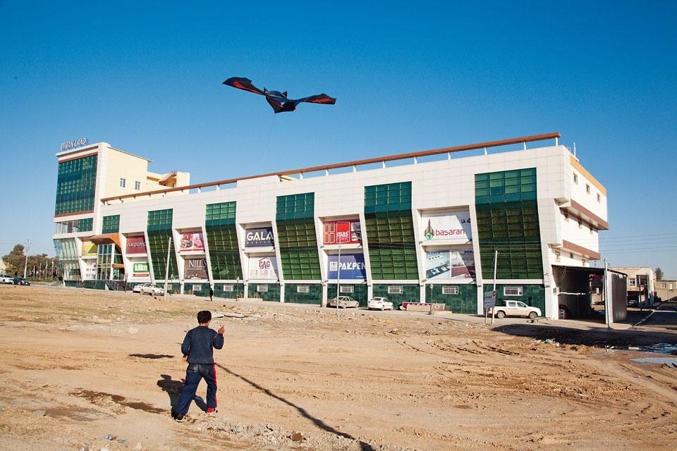 A boy flies a kite near
a new row of stores in Erbil