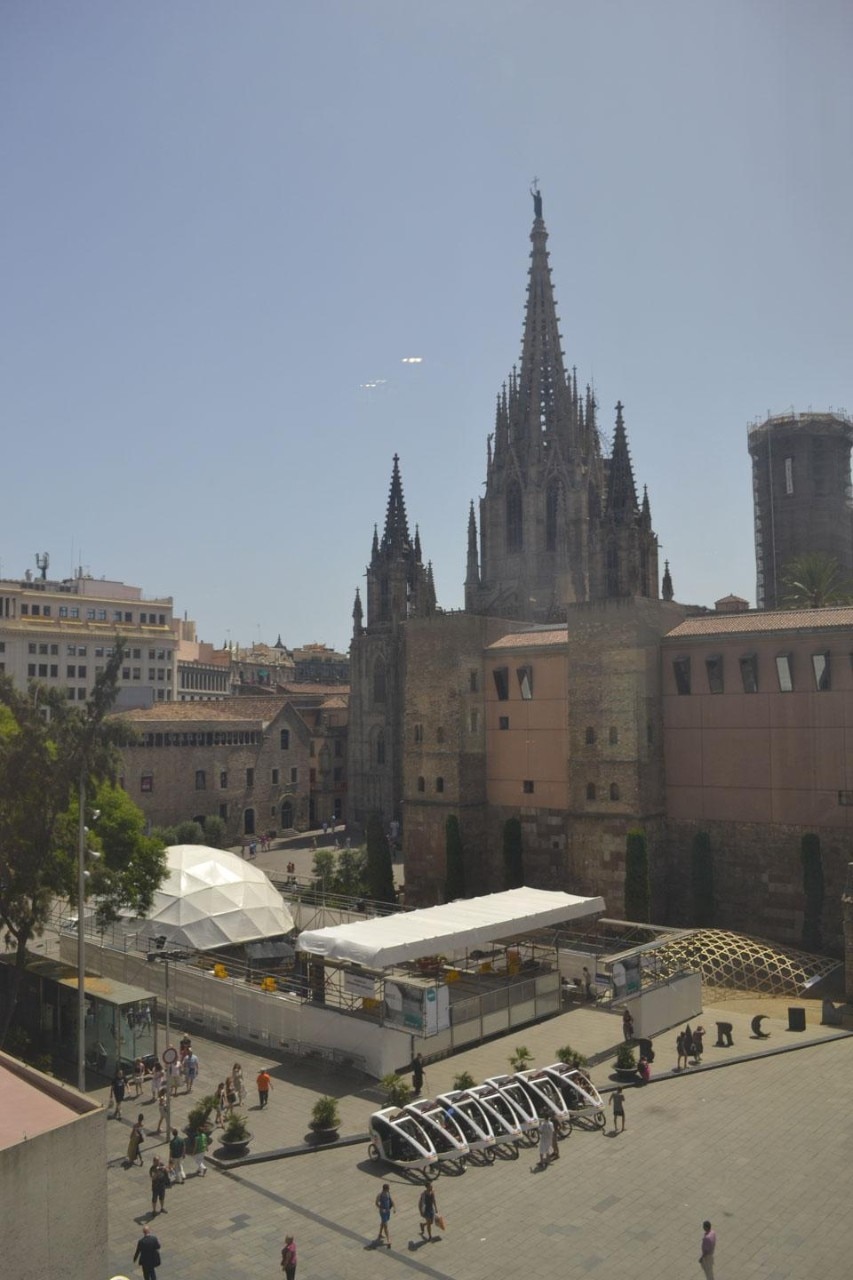 Overview of the Eme3 plaza, with the M1 project, an itinerant dome set up in the Cathedral Plaza in front of the COAC, and surrounded by a fence with an entry opening