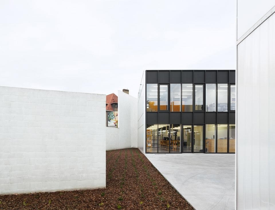 The outdoor patio of an
informatics company in Tielt.
Two volumes, identical in
form and scale, face the
same courtyard. The site’s
irregular boundary is
emphasised by the architects
with a brick wall. Painted
white, it varies in height