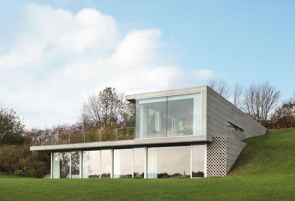 Top: The hills around Liège are
the last thing the inhabitants
of this house see before
descending into its domestic
depths through a curved
opening. Above: Standing on a natural slope,
the house comprises two
superimposed volumes of
Cartesian linear geometry,
set perpendicular to one
another