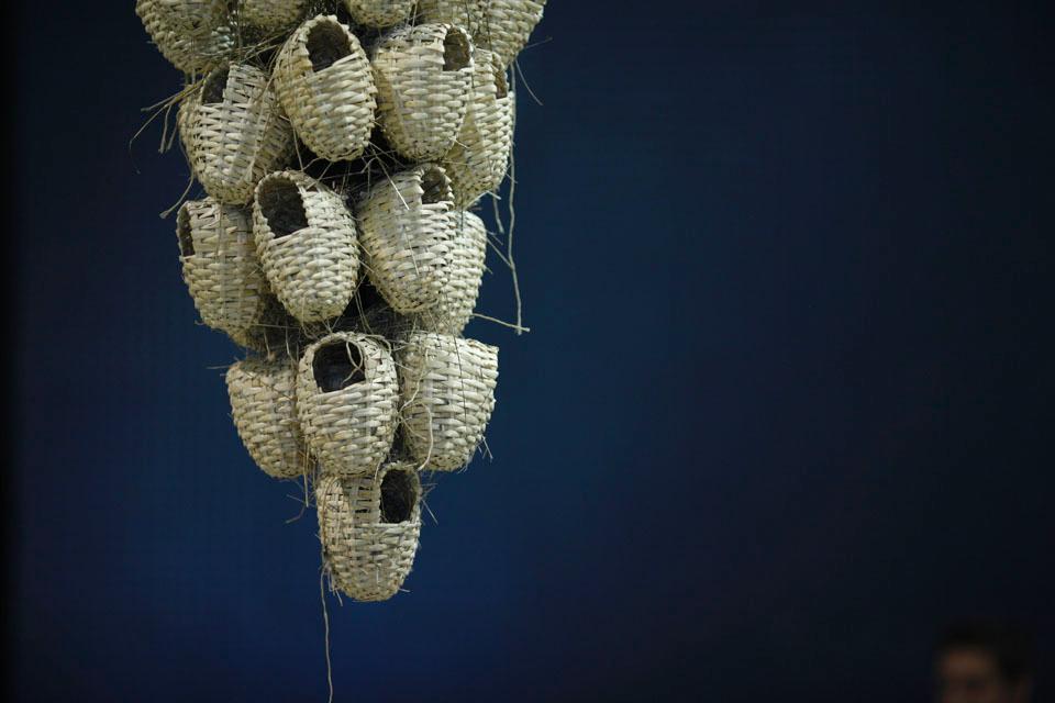 A cluster of straw nests hangs in the center of the installation. 