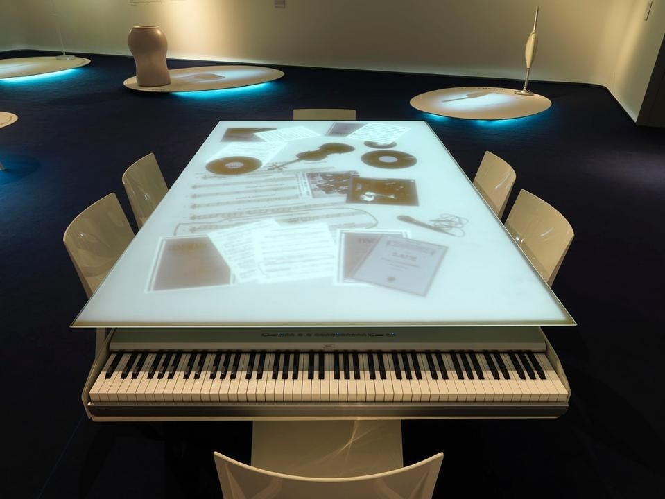 The prototype of Flat Piano, a combination of a piano and a dining table. Amplifiers under the table distribute the sound across the entire surface.