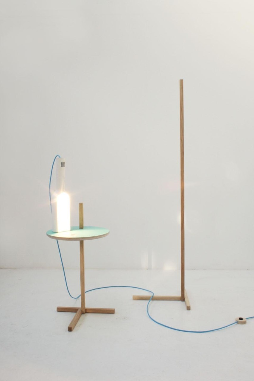Designed by Tomas Alonso, the Bottle light is a side light in ceramic that can be used either on its own or on a stand, a simple wood post to which the light clings on to by applying a basic cantilevering system. This makes the light easily adjustable in height relying just on its own weight to stay at the desired position. 
