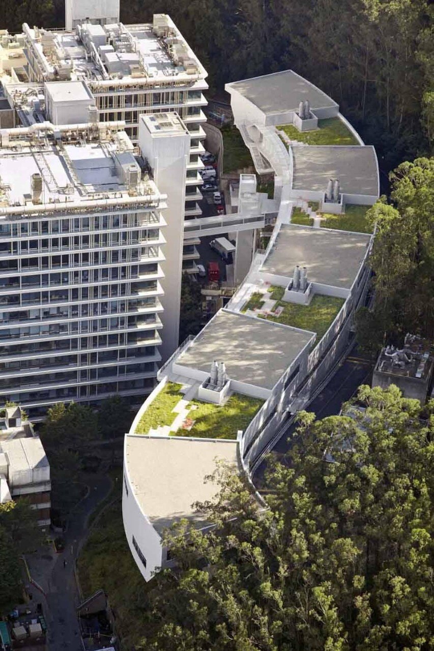 The main floor is divided into four split levels, each stepping down a half-story as the building descends the forested mountain slope, and each topped by an office cluster and a green roof
