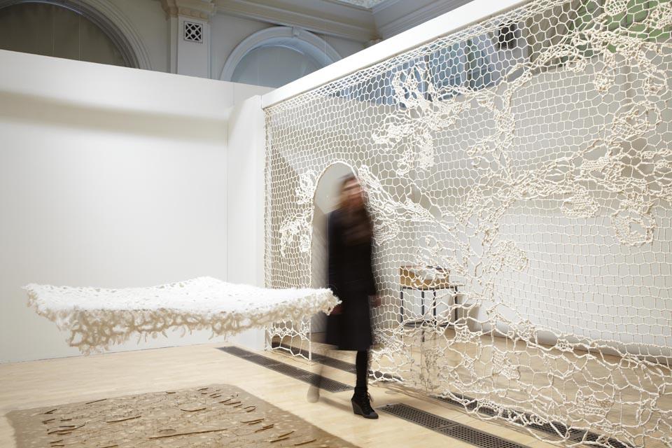 Annie Bascoul will display two existing pieces that work together as an
installation. Viewers enter the installation through a doorway in
Moucharabieh, a large-scale cotton screen created using the Alençon
lace technique. As they enter they will see Jardin de lit, lit de jardin, a
cotton and feather bed that floats above a brass wire version of the
erotic 16th century poem Le May