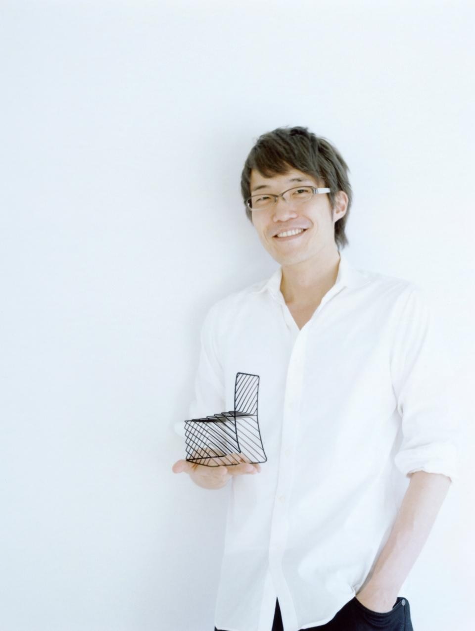 Oki Sato, Nendo co-founder with Akihiro Ito, holding a miniature of the <em>Thin Black Lines</em> collection chair