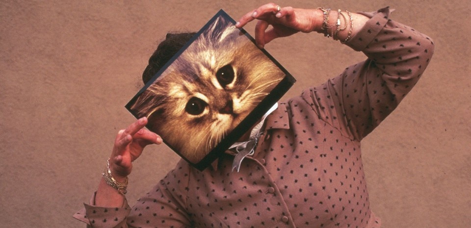 Ray Eames posing with a cat photograph, December 1970. © Eames Office LLC