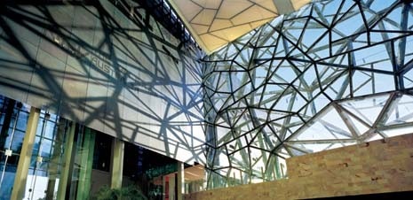 The glass and steel reticular structure creates a geometric pattern of light and shade on the front of the National Gallery of Victoria
