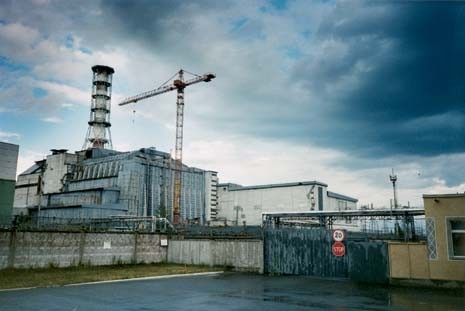Chernobyl Nuclear Power Station in 2003: the closest view that radiation levels and intense security allow visitors to get of the former nuclear reactor. The cascading wall to the left and the tall buttressed wall to the centre, both implemented after the explosion in 1986, are closely monitored for structural decay and water penetration. The small visitor centre stands to the right of the picture