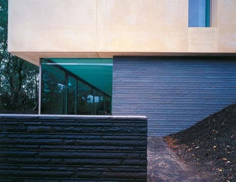 The house sits on a masonry base, above, cut into the slope of the hill. The upper level is plaster