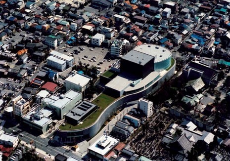 The building is located close to the centre of Matsumoto, on a site flanked by a typical residential neighbourhood to the east, a Shinto shrine to the south and a major high street to the west. The elongated form of the plot led the architect to rearrange the condensed layout of the conventional theatre, resulting in an embryonic form that slices through the urban landscape. Photo by Miyagawa