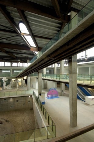 Visitors circulate via an external corridor 
and by ramps, cantilevered onto the tapered pillars that cross the central void and connect 
the building’s floors
