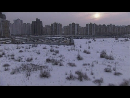 <i>Desniansky Raion</i>, 2007.
Made up of three parts, the film alternates scenes of order and chaos. It opens with a static shot of a ’70s high-rise housing block, a monumental triumph-gate built at the entrance of Belgrade. The film questions man’s traces in nature, between vandalism, romanticism and land art. Courtesy Cosmic Galerie (Bugada & Cargnel), Paris <i>Desniansky Raion</i>, 2007.
Made up of three parts, the film alternates scenes of order and chaos. It opens with a static shot of a ’70s high-rise housing block, a monumental triumph-gate built at the entrance of Belgrade. The film questions man’s traces in nature, between vandalism, romanticism and land art. Courtesy Cosmic Galerie (Bugada & Cargnel), Paris