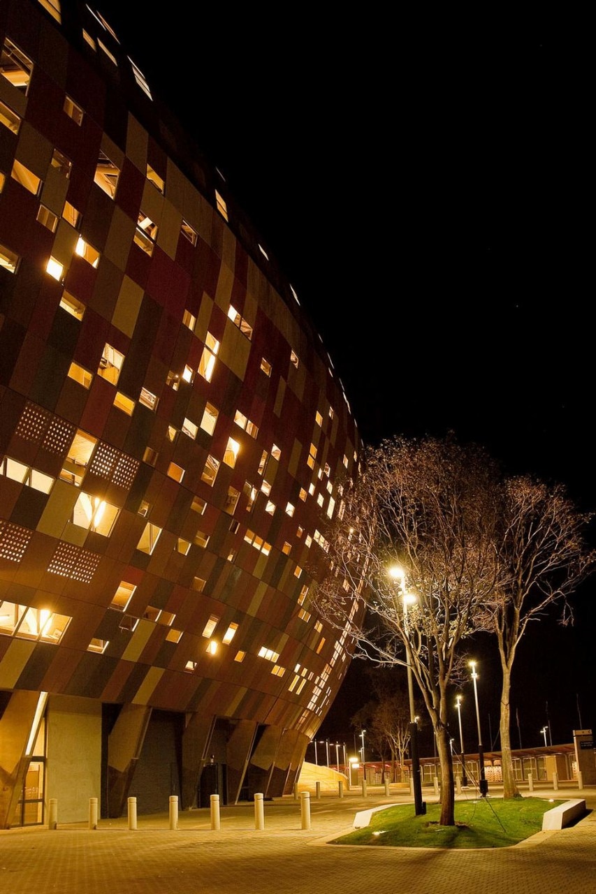 The facade of the Soccer City Stadium is
formed with a continuous texture of panels
in eight different colours, perforated
irregularly by a network of minute holes.
Produced by Rieder Smart Elements GmbH,
the panels (FibreC) are made of a concrete
and fibreglass mixture. The surfaces are
coloured by adding iron oxides and natural
additives before the concrete has set