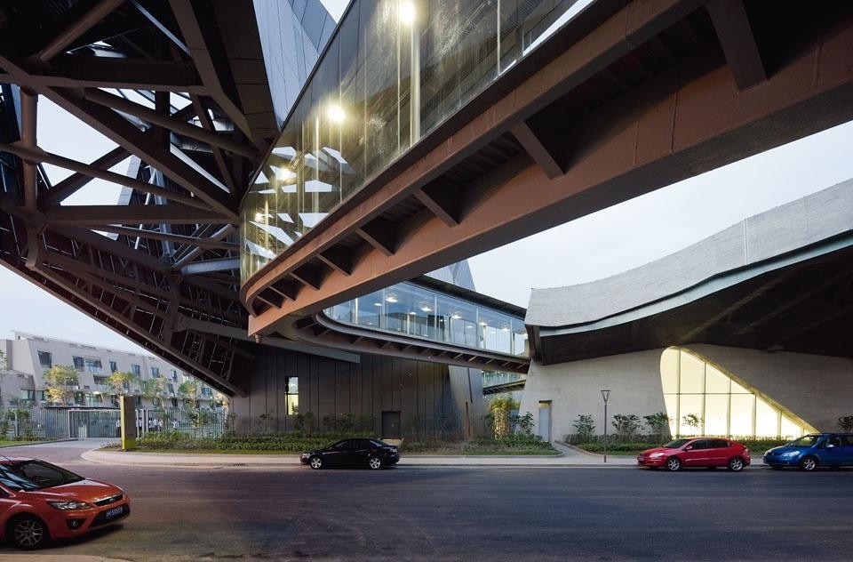 Divided into two blocks, the campus is crossed by a newly built road. A large gridded bridge structure connects the two wings of the campus.