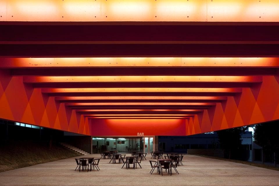 Night view of the covered square of the Garcia de Orta middle school in Porto. In the background, the bar entrance