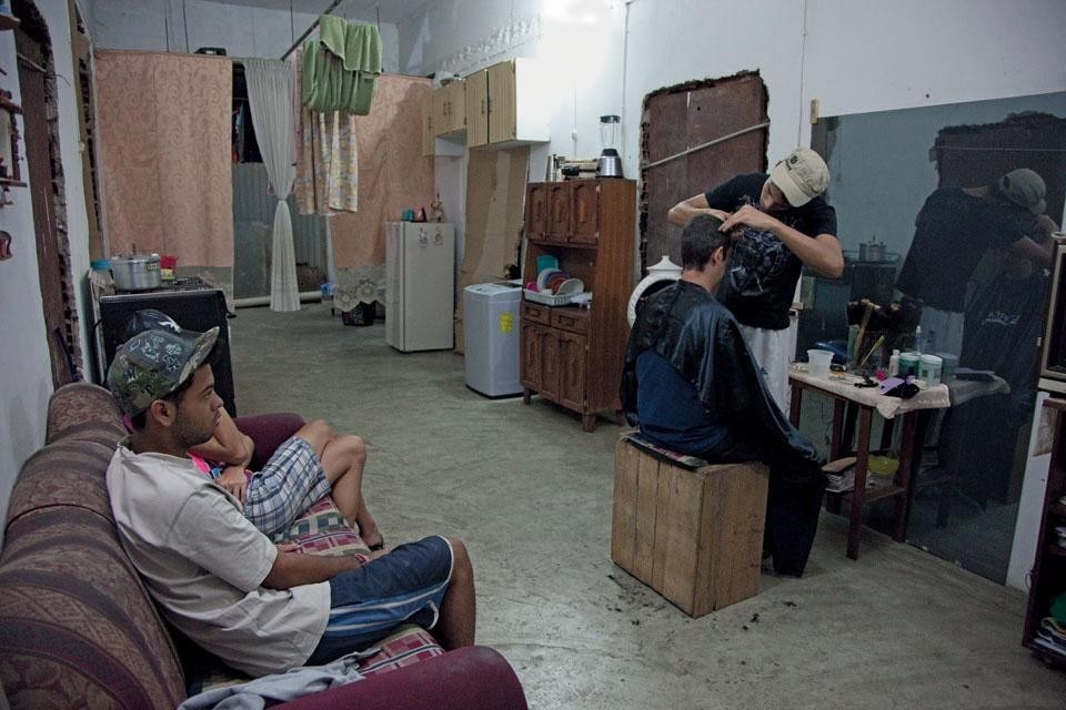 Roinner Hernández (aka
Ronny), 20, works in a
prestigious hair salon in the
southeast of Caracas but also
receives clients in his apartment
on the 4th floor of the tower.
As a mirror, he uses a sheet of
glass taken from the facade of
the tower.