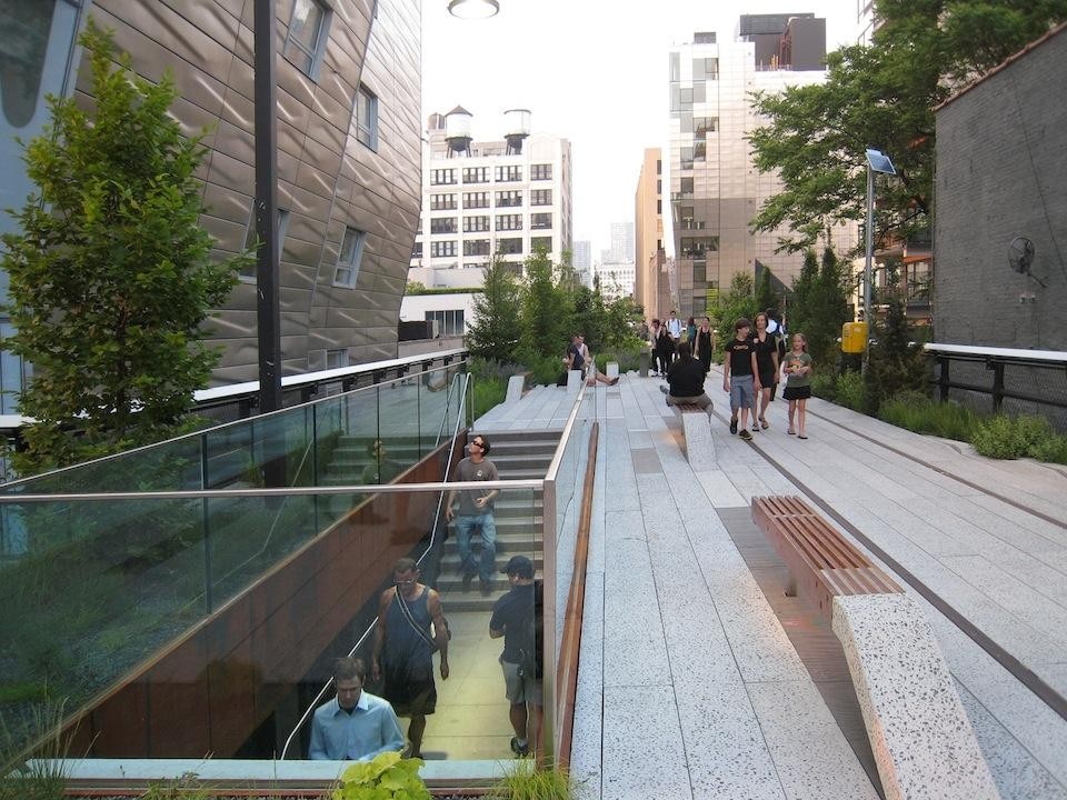 The cutout entrance stair on the High Line at West 23rd Street, passing through old and new architecture. Materials include Corten steel, glass panels, cast concrete, Ipe wood, and plantings rooted in 18 inches of turf, supported by the original 1934 rail structure. © Gideon Fink Shapiro.
