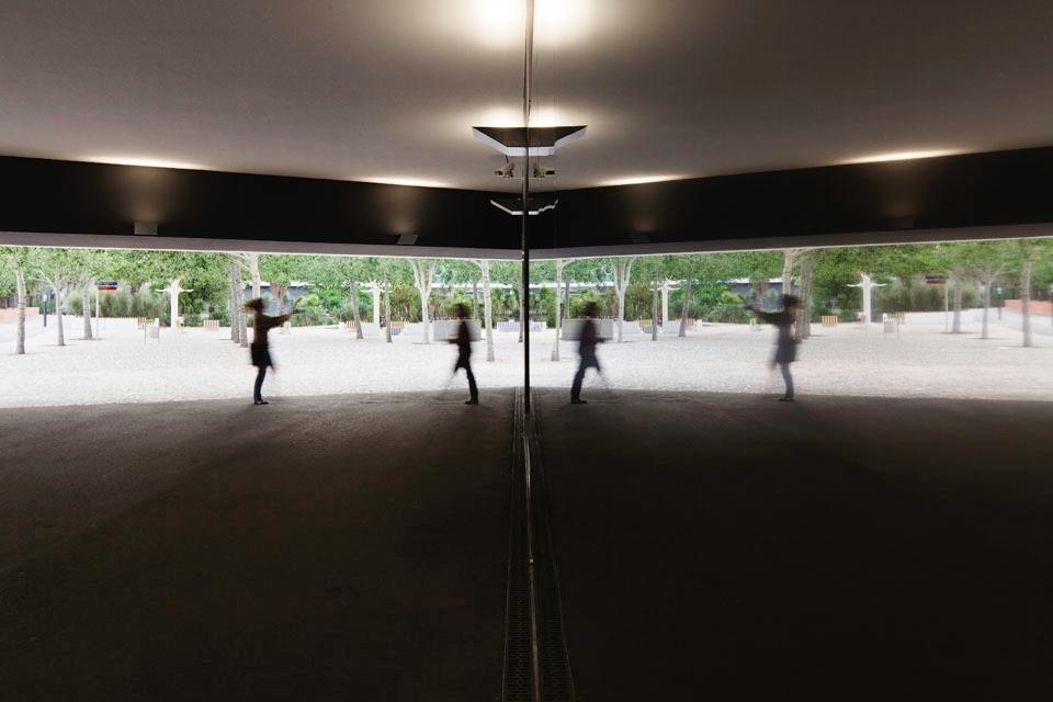 Top image: View of the building with the existing plaza and fountains. Above: the mirrored wall in the building entrance. The projecting volume transforms the entry space into a covered plaza modulating the transition between interior and exterior. Photo © <a href="www.brunecky.com" target="_blanK">Radek Brunecky</a>
