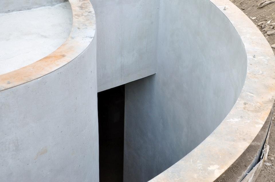 Exposed concrete curved staircase to level -1. Photo by SO – IL.