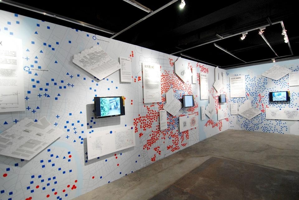 Top: the mirror-lined gallery displays the product of a six-day workshop with students at Rotterdam's Berlage Institute, in which six different groups were given 200 foam cubes a day and asked to build a layer of a vertical village according to six vaguely defined agendas. Above: Case studies of existing urban villages across nine Asian cities are analysed with quantitative data, alongside maps of their erasure by the "block attack" of new towers.