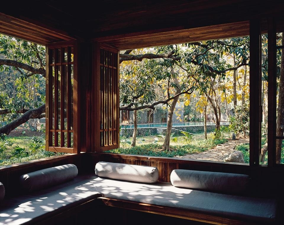 5.	The corner of the veranda accommodates a built-in sofa. From here, a swimming pool can be glimpsed through the trees