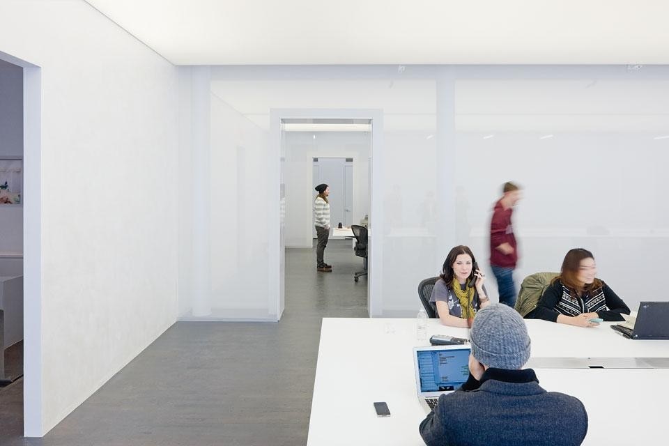 The Logan offices in SoHo, New York. The false ceiling in PVC
reflects natural light without
casting shadows. The end
section of the continuous
table is separated from the
rest of the room by a glazed
wall to create an acoustically
insulated space