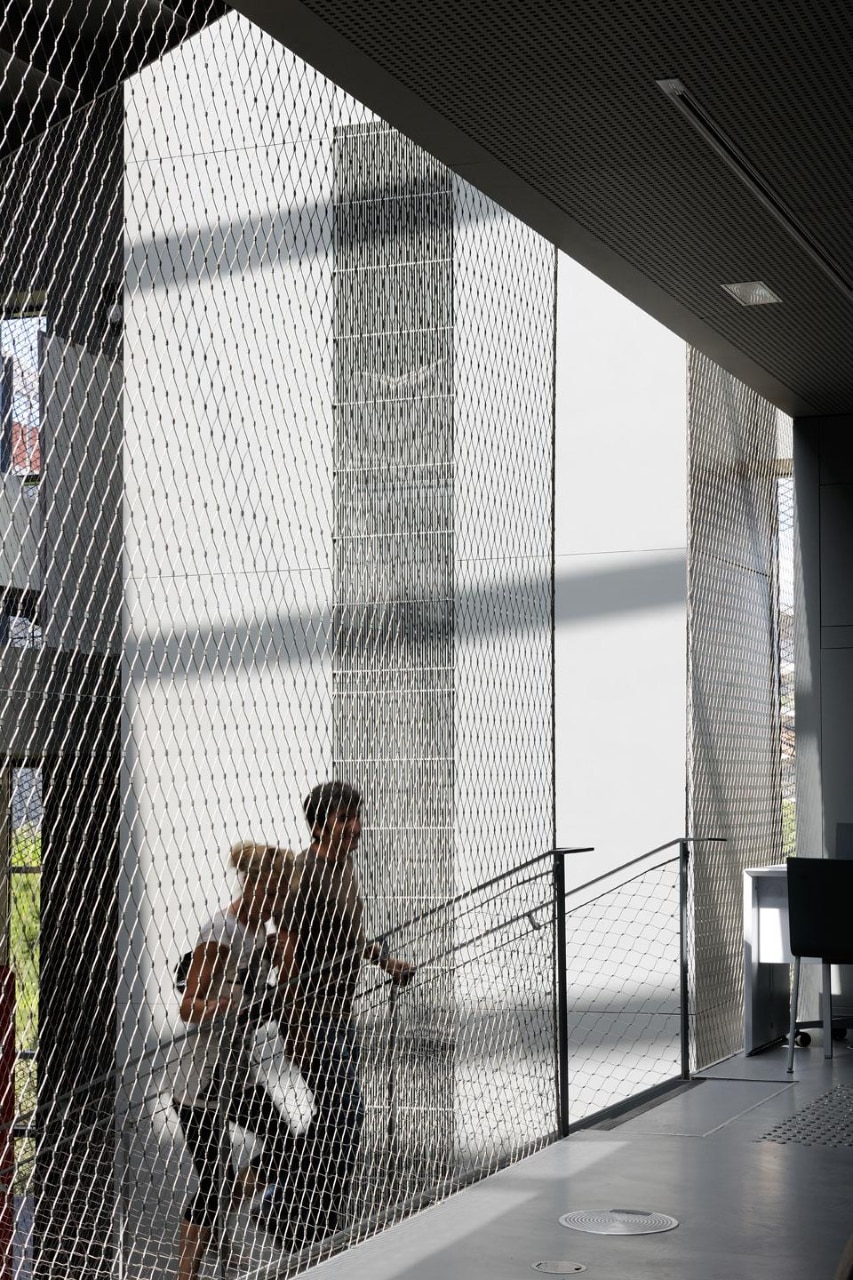 Detail of the stairs; a metal mesh circumscribes the central courtyard. Photo by E. Saillet