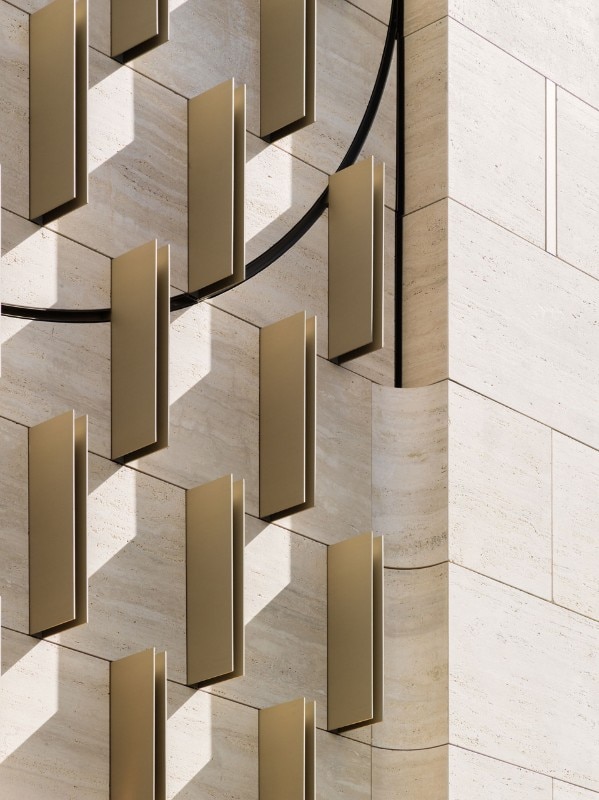 Detail of the facade in travertine marble and brass details