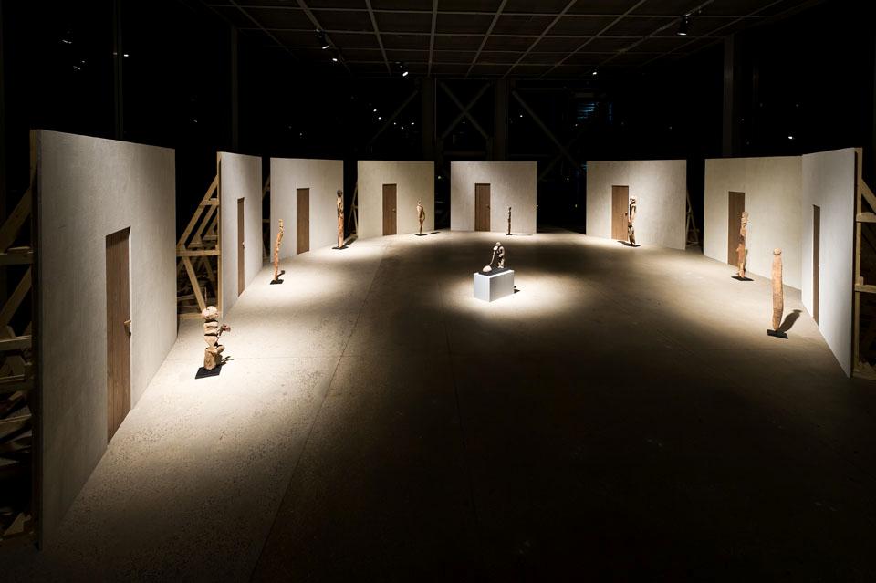The arrangement by Enzo Mari suggests the solemnity of a simple village with its doors closed and the figures of guardians who protect the secret of their interiors.