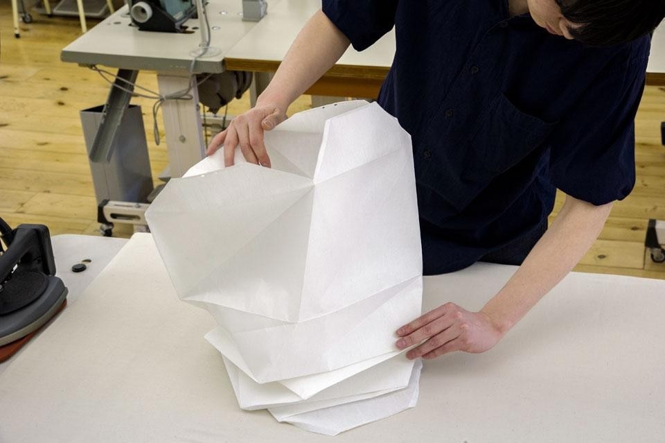 The
shade is diagonally folded by
hand using an iron to prepare
for the next pressing process