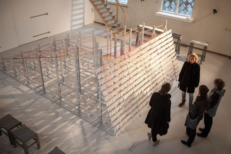 Atelier NL's <em>Curious Minds</em> installation is a large information map that charts the career paths of Design Academy graduates from 2006 to 2011, stretching coloured threads over a large wooden space frame. Photo by Mike Roelofs
