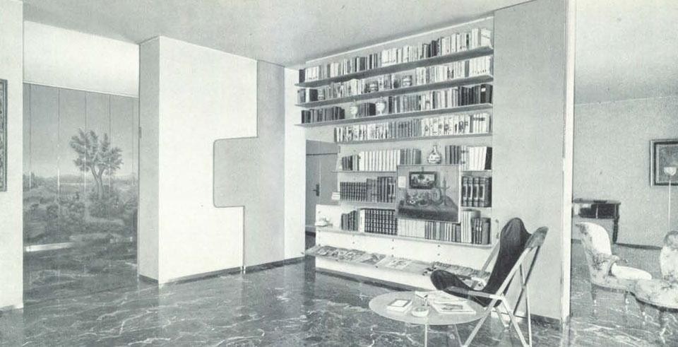 The library wall divides the study from the living room. Note, on the left, the door that closes the opening of the same shape; on the right, a folding door can completely isolate the environment