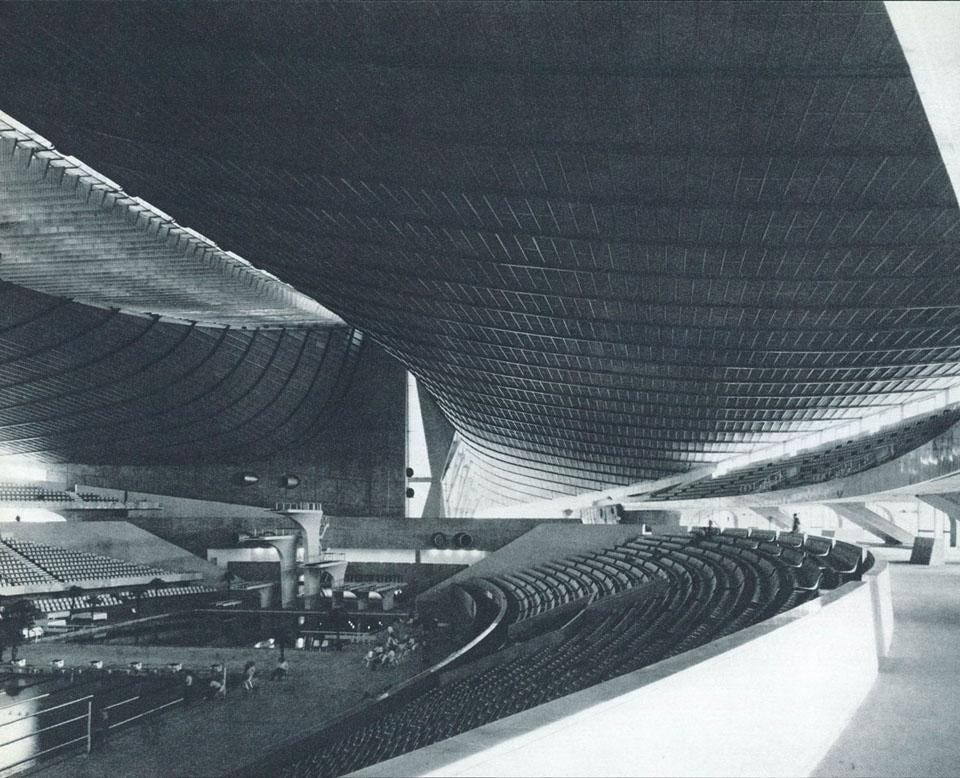 In the Swimming Stadium, the sickle-shaped stands. The upper “sickle” forms a large inclined arch that keeps the roof “tent” attached and in tension