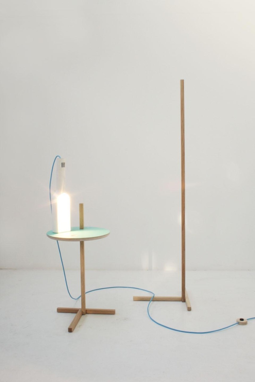 Designed by Tomas Alonso, the Bottle light is a side light in ceramic that can be used either on its own or on a stand, a simple wood post to which the light clings on to by applying a basic cantilevering system. This makes the light easily adjustable in height relying just on its own weight to stay at the desired position. 
