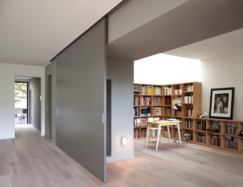 Giant sliding walls on each floor divide into two day spaces in order to currently organize a new partition of the areas and create an office/library on the ground floor area and a cinema on the first floor, Eco-Sustainable House by Djuric Tardio Architectes.