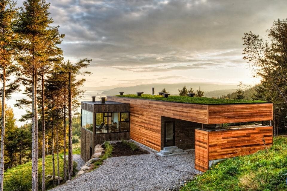 A wide gateway acting as a carport and covered entrance rests on a retaining wall/storage unit that was necessary given the condition of the very steep terrain