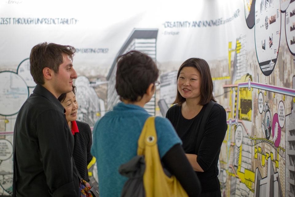 Top: Höweler + Yoon are the winners of the 2012 Audi Urban Future Award with their “Shareway” project for the Boston-Washington metropolitan region. Above: Meejin Yoon and Eric Höweler in conversation with two visitors. In the background, the project Urban Parangolé by Urban-­Think Tank (São Paolo, Brazil). Photo © Audi Urban Future Initiative