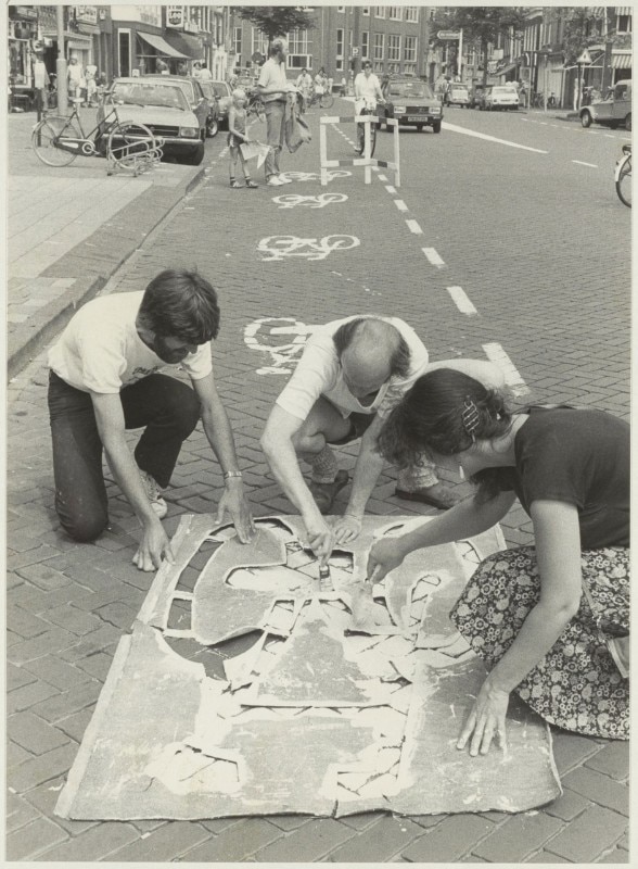 I membri dell’Unione Ciclisti intervengono sulla Gedempte Oude Gracht applicando stampe per segnare la pista ciclabile. Immagine scattata fra il 1984 e il 1986. Immagine via Wikimedia Commons – Noord-Hollands Archief / Fotoburo de Boer