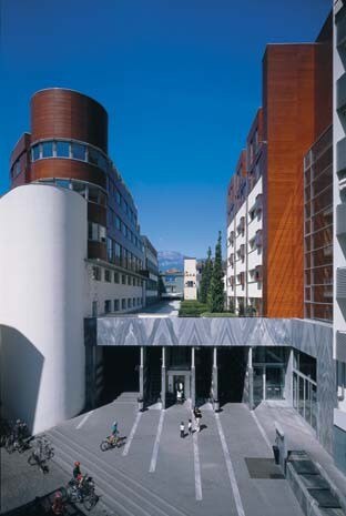 Il progetto, nel centro di Bolzano, ha integrato edifici storici con nuovi blocchi. Il complesso, che comprende un centro commerciale, abitazioni, uffici e lo storico hotel Greif, si articola intorno a una lunga galleria coperta. A destra, i collegamenti verticali che dalla piazza portano al livello del centro commerciale e del passaggio coperto 