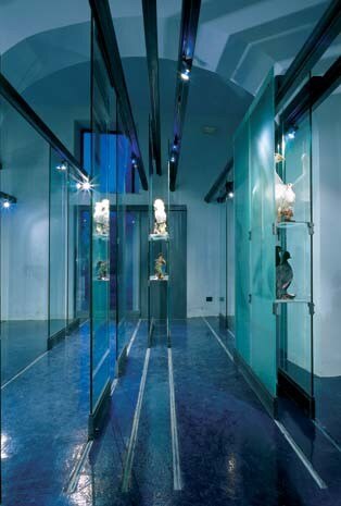 Il cristallo richiama le proprietà di riflessione e trasparenza dell’acqua. Lo spazio è ricavato in un edificio inserito nel complesso della Rocca del Castello dei Savelli, il cui nucleo originale risale al XIII secolo
