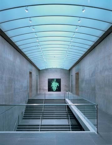Alla sommità della scala principale, un autoritratto di Warhol – spaventoso come un demone giapponese – è fissato a una parete priva di aperture