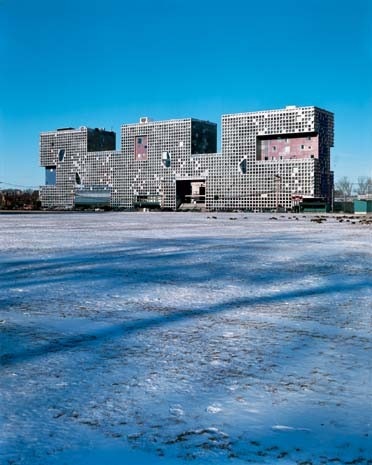 Il monolite solitario di Holl si allunga per 140 metri lungo il bordo di un’area aperta. Studiate variazioni volumetriche interrompono il blocco compatto e modulare 