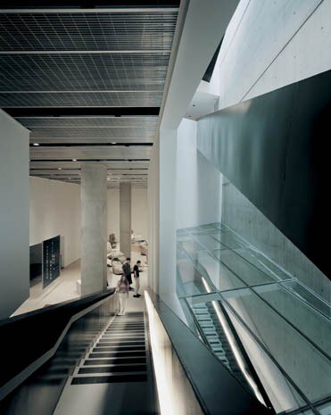 L’ingresso invita i visitatori nell’atrio luminoso che sale verso l’alto: primo gradino di una serie di passerelle che conducono a un intreccio di scale, talvolta incrociate agli spazi espositivi, talvolta ben distinte da essi