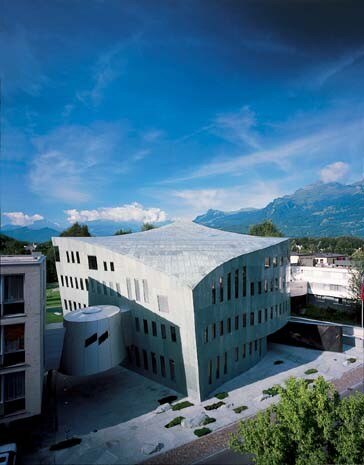 Malgrado sembri una pietra tagliata, l’edificio sorprende per la sua forma particolare. Costruito a forma di cubo, acquista dinamismo grazie alla linea arcuata del tetto e all’inclinazione delle pareti