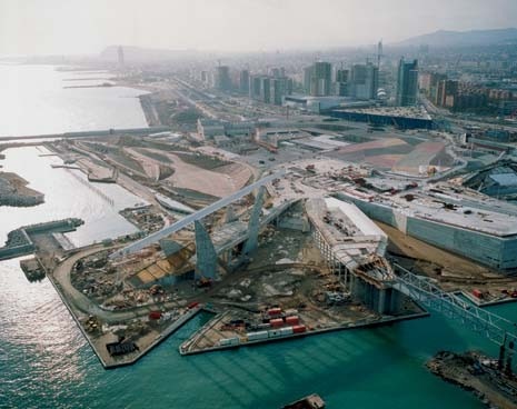 In primo piano, il nuovo porto turistico, la pensilina con i pannelli fotovoltaici e il suolo artificiale di Lapeña e Torres; sullo sfondo, l’edificio di Herzog & de Meuron, e il Centro Congressi di Mateo