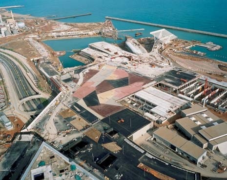 Un nuovo porto turistico, il completamento del sistema delle spiagge di Barcellona e un grande suolo artificiale, quasi un edificio, che accoglie tutte le vecchie e nuove infrastrutture, dai depuratori ai nuovi servizi portuali. Il mosaico di asfalti colorati circonda il Palazzo dei Congressi di Mateo e l’edificio di Herzog & de Meuron